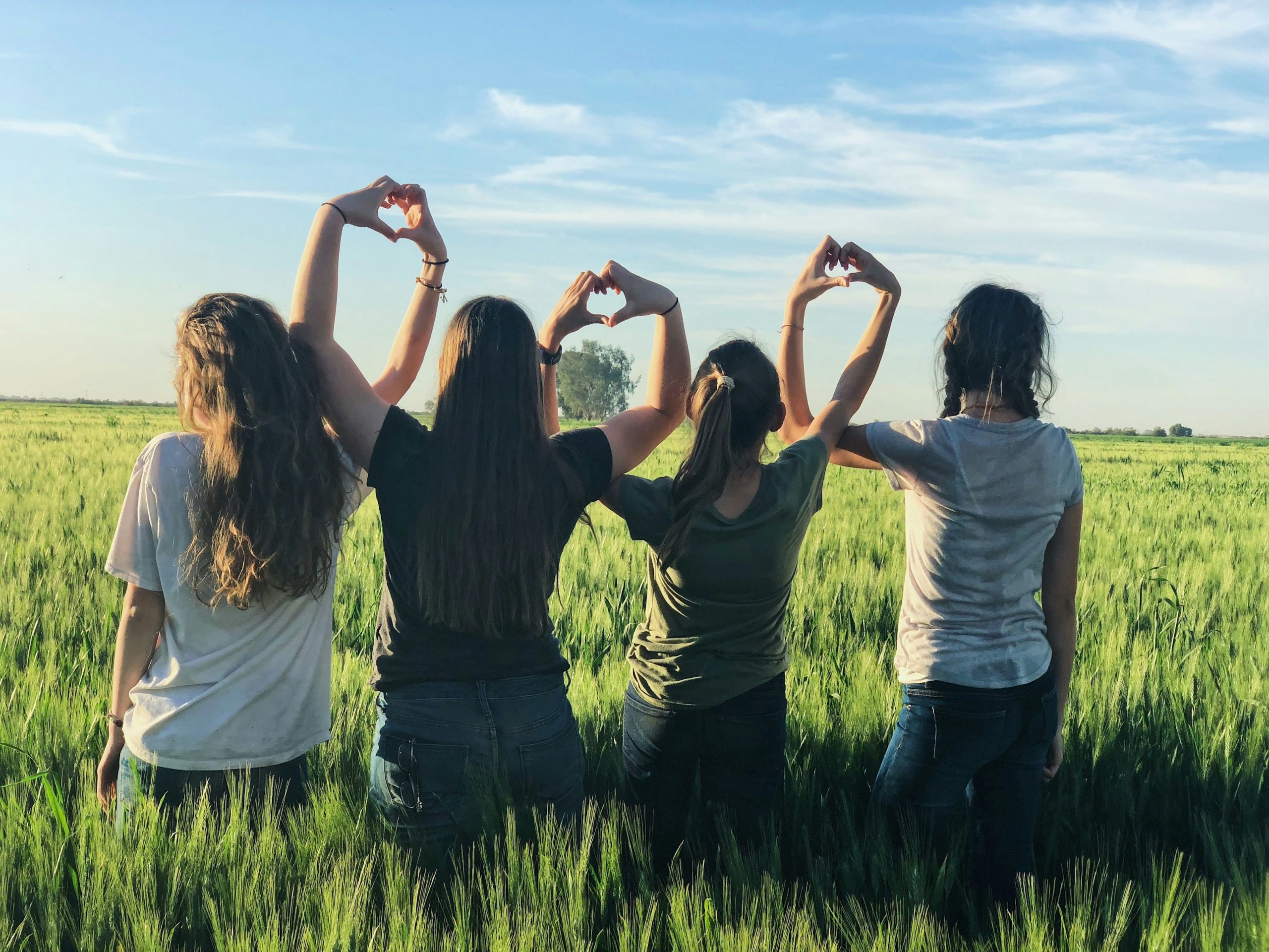 women making heart gesture in farm work abroad