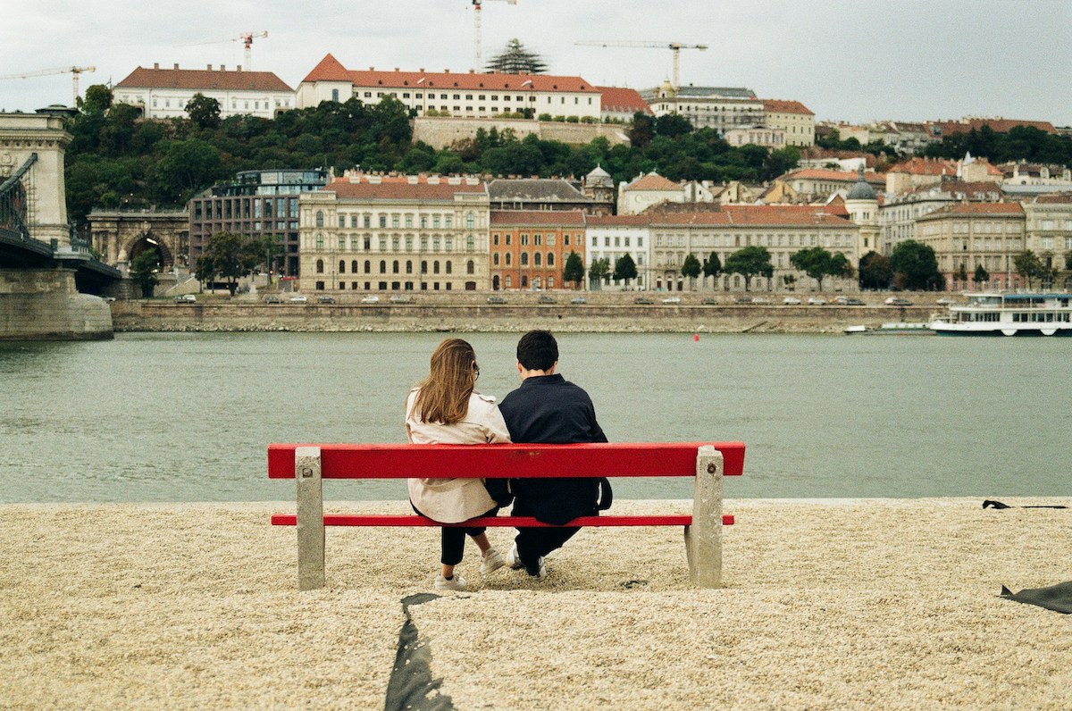 A man and a woman sitting on a red bench in Budapest, Hungary