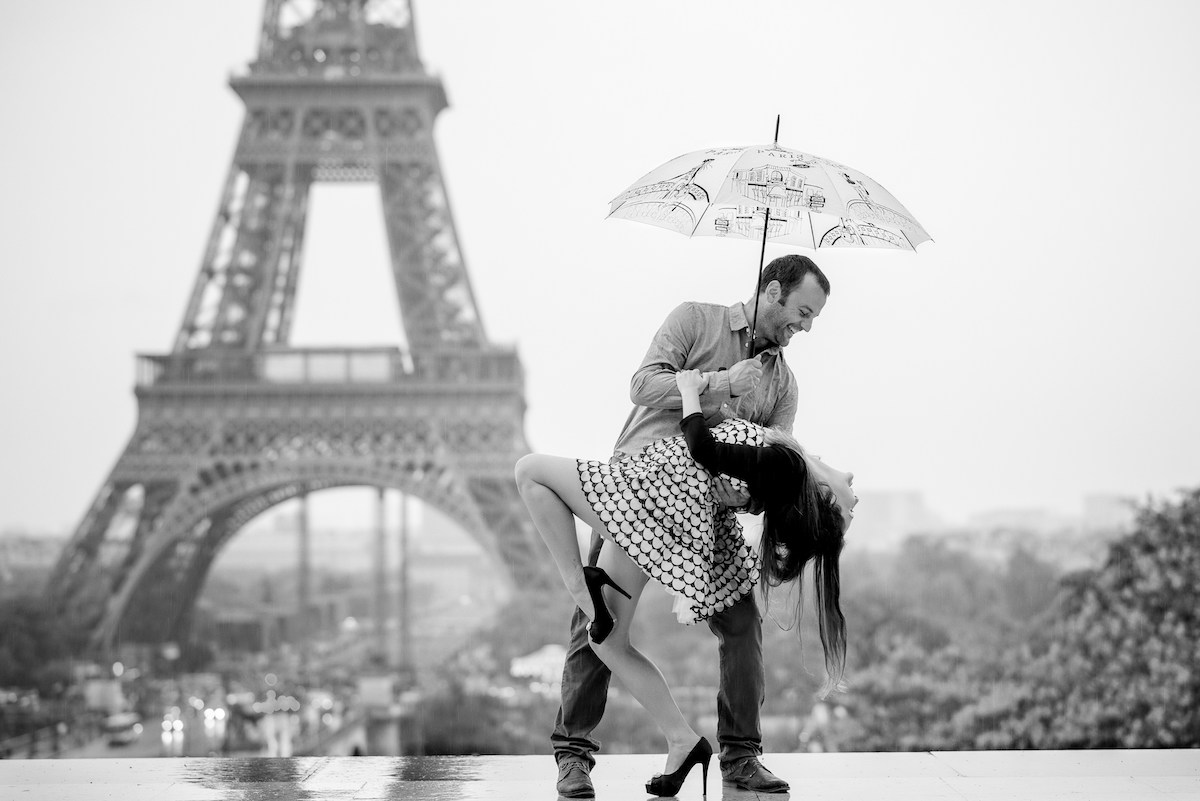 Couple dancing in the rain in front of the Eiffel Tower.