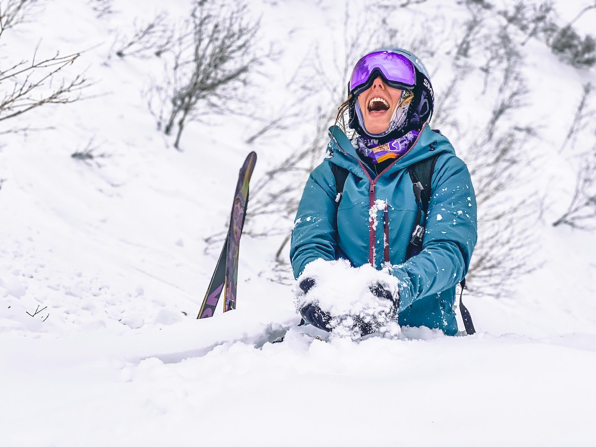 Person in blue jacket laughing in the snow