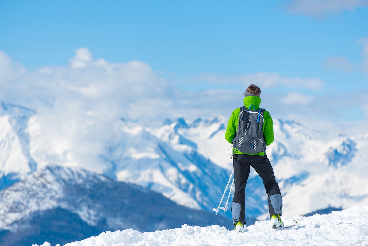 A person standing on top of a snow mountain looking over slopes